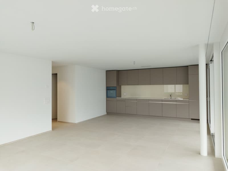 Open kitchen area with large windows, embedded oven, sink, cabinets