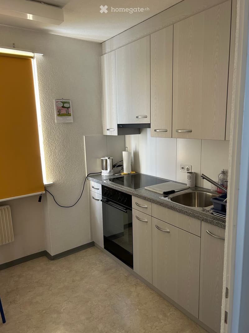 Modern kitchen with light wood cabinets, granite countertop, stainless steel sink, electric kettle, and small appliances.