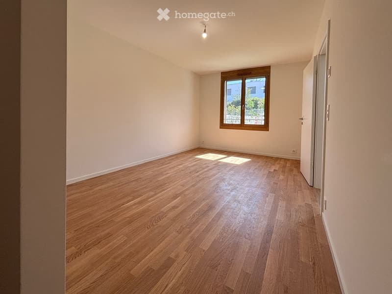 Empty room with wooden flooring, white walls, and a single window with wooden frame. No furniture or equipment present.