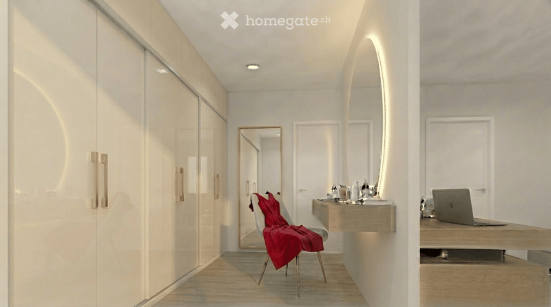 Modern, minimalist room with a sleek wardrobe, a large mirror, a wooden table with a laptop, and a chair with a red blanket draped over it.