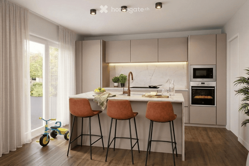 Modern kitchen with light-colored cabinets, a central island with bar stools, and built-in appliances including an oven and microwave. The island features a marble countertop with a sink and faucet, and there are decorative plants and a small child's tric