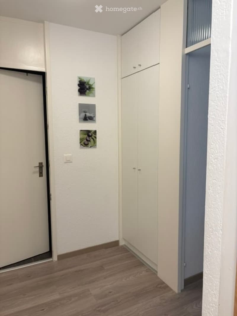 Empty room with white walls, wooden flooring, white built-in closet, and three small framed pictures on the wall.