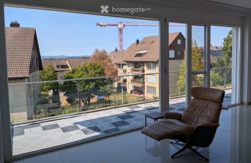 Modern balcony with glass railing, tiled floor, leather chair, small table, and scenic city view.