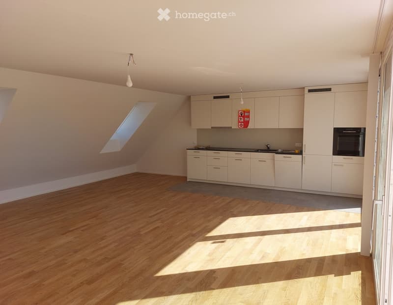 Bright kitchen with light-colored cabinets, a sink, and an oven. The floor is wooden, and there is a skylight providing natural light.