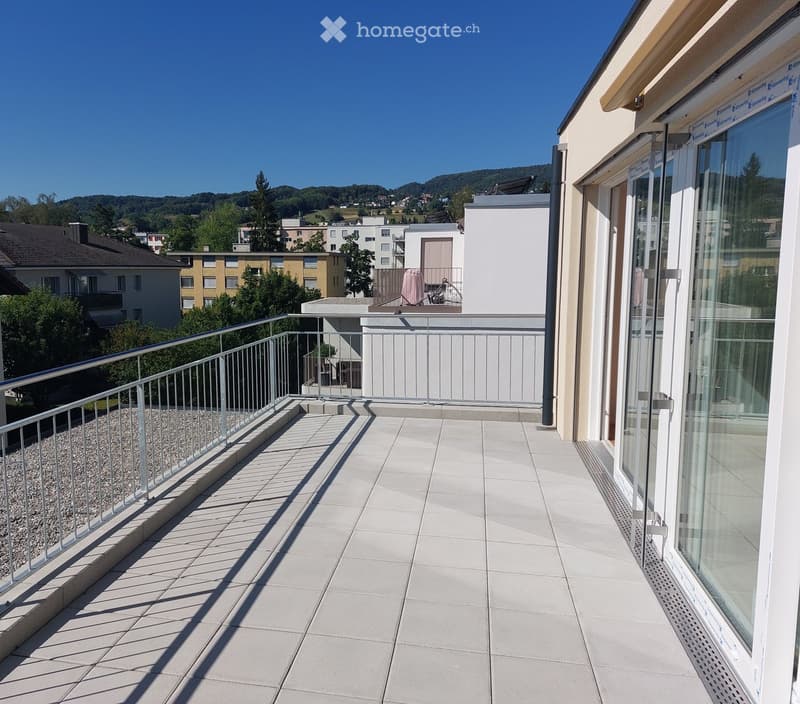 Balcony with tiled floor, metal railing, and scenic view of surrounding buildings and landscape.