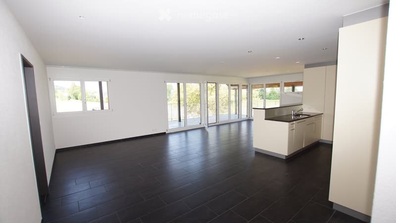 Modern kitchen with dark tiled floor, white cabinets, and large windows with sliding glass doors leading to a balcony.