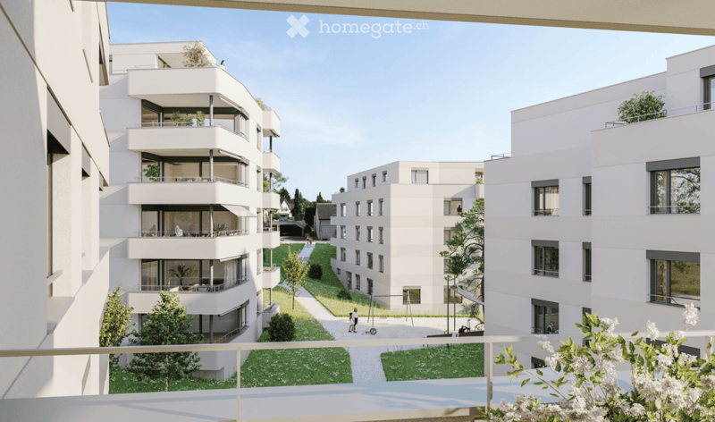 Modern residential complex with multiple white apartment buildings, balconies, greenery, and pathways.