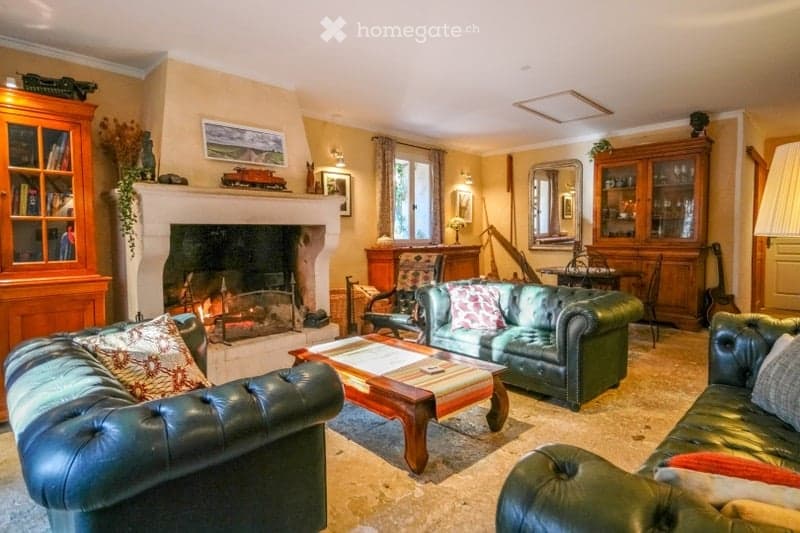 Cozy living room with a fireplace, leather sofas, coffee table, wooden cabinet, and a guitar in the corner.