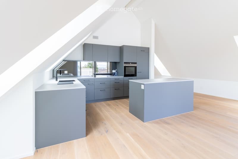 Modern kitchen with grey cabinets, white countertops, and wooden flooring. Features a sink, faucet, and built-in oven.