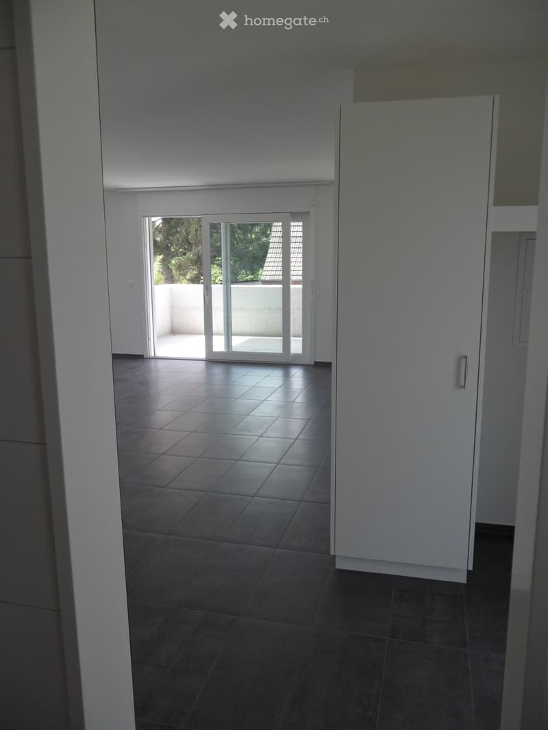 Empty room with tiled floor, white walls, and sliding glass doors leading to a balcony or outdoor area.