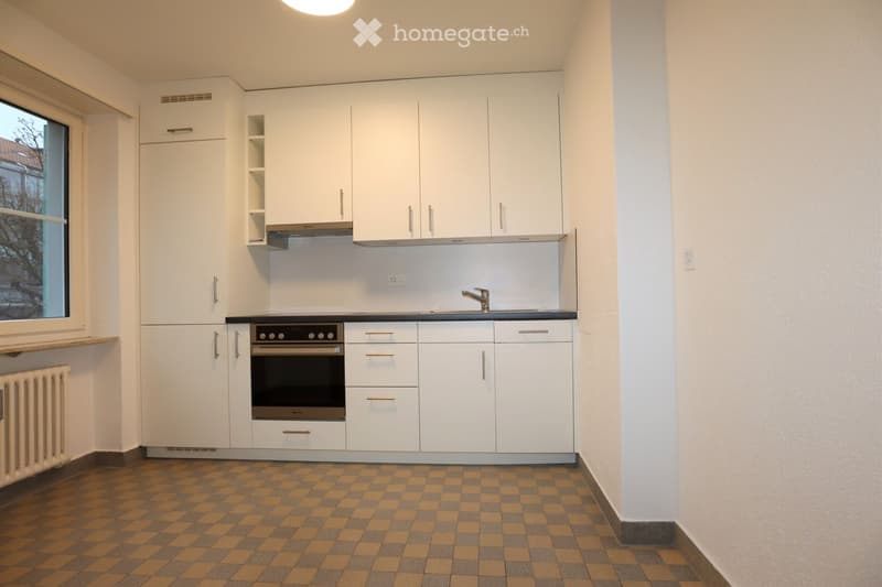 Modern kitchen with white cabinets, a built-in oven, a sink with a faucet, and a window offering a view of the outside.