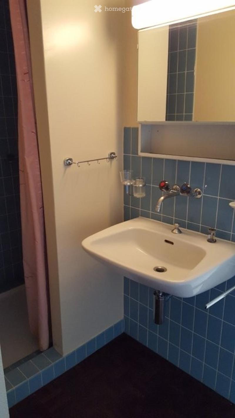 Small bathroom with a white sink, chrome faucet, mirror above, and a towel rack on the wall.
