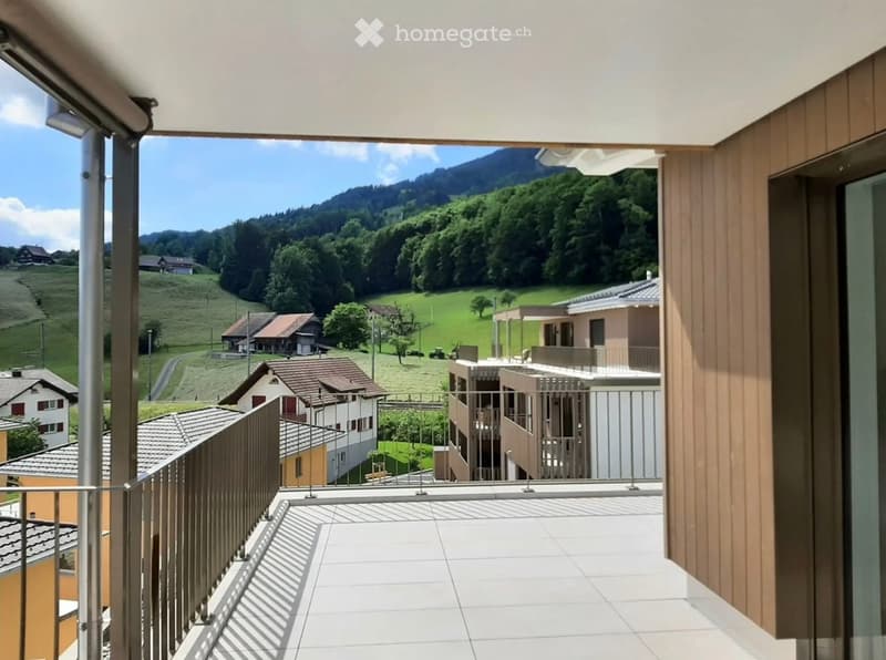 Balcony with white tiled floor, metal railing, and scenic mountain view of green hills and houses.