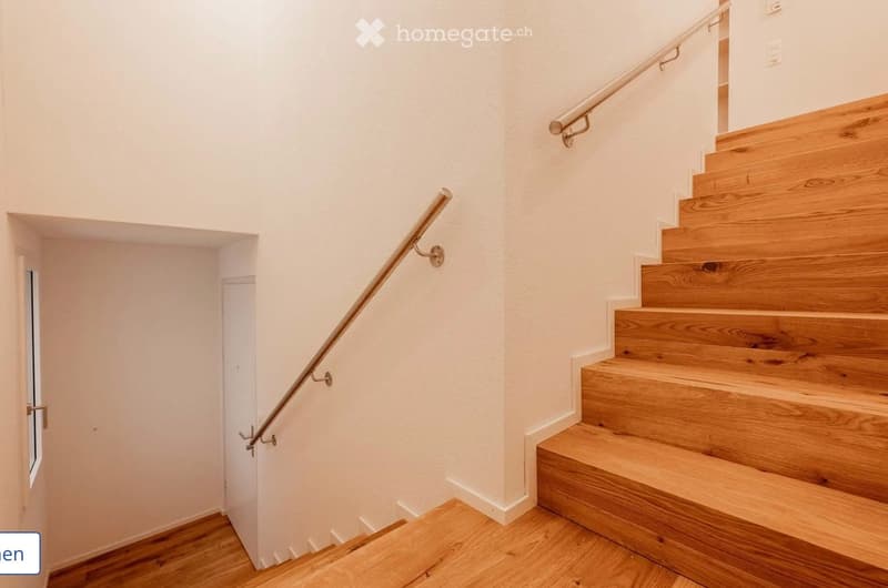 A modern wooden staircase with a metal handrail, white walls, and a small window on the left side.