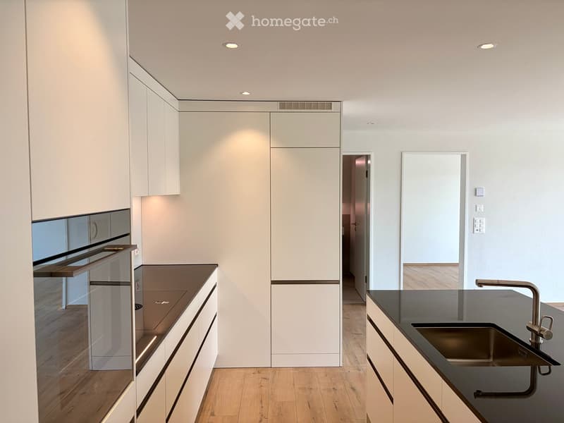 Modern kitchen with white cabinets, dark countertops, and a stainless steel sink with a modern faucet.