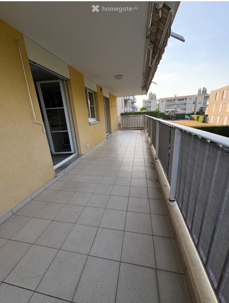 Balcony with tiled floor, metal railing, and sliding glass door leading to the interior.