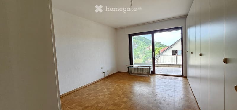Empty room with wooden flooring, white walls, and a large sliding glass door leading to a balcony with a scenic view.