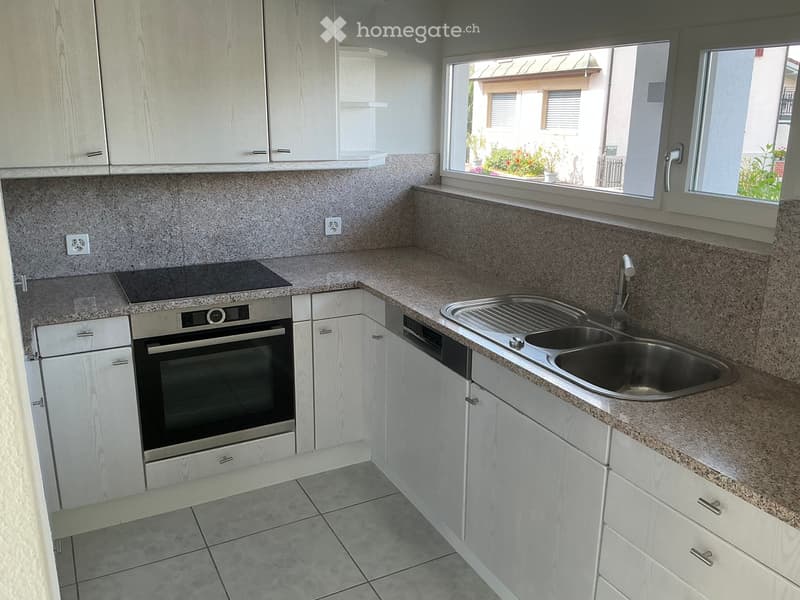 Modern kitchen with white cabinets, granite countertops, stainless steel sink, and built-in oven.