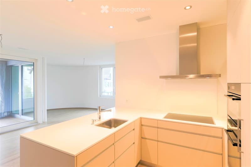 Modern kitchen with light-colored cabinets, a central island, and a stainless steel sink and oven.