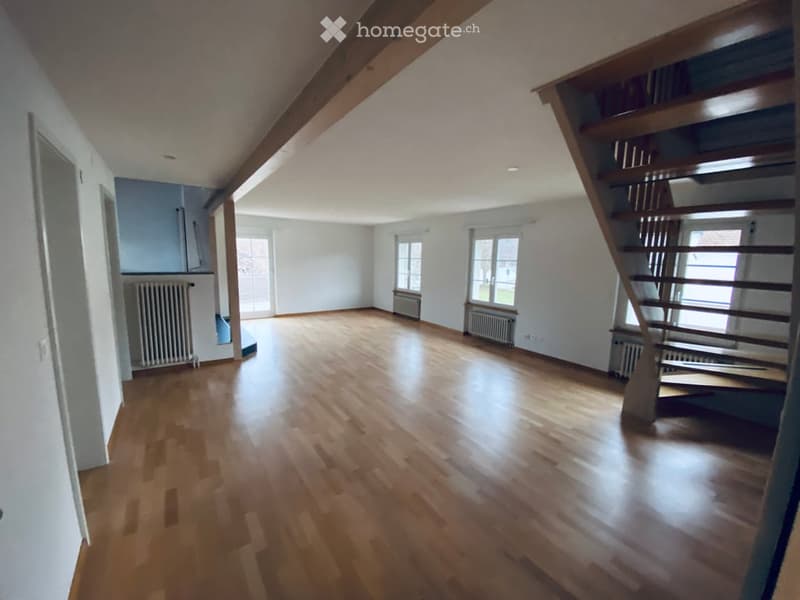 Empty room with wooden flooring, white walls, and a staircase leading upwards. No furniture or equipment present.