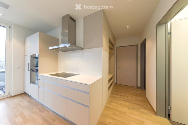 Modern kitchen with light-colored cabinets, stainless steel appliances, and a central island with a built-in stovetop.