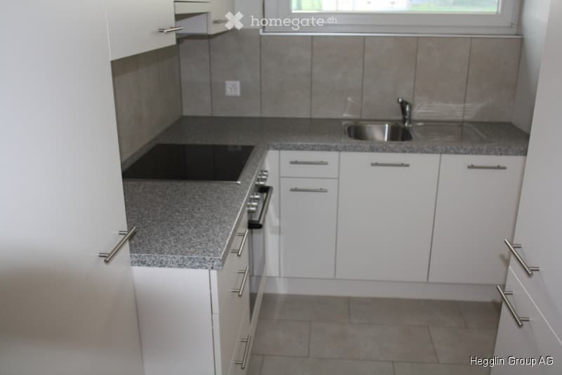 Modern kitchen with white cabinets, granite countertops, and stainless steel appliances including a stove and sink.