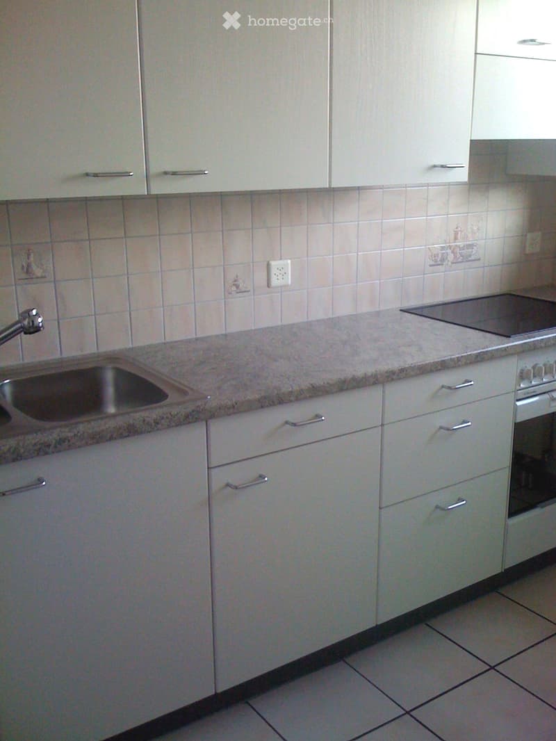 Modern kitchen with white cabinets, granite countertop, stainless steel sink, and built-in oven and stove.