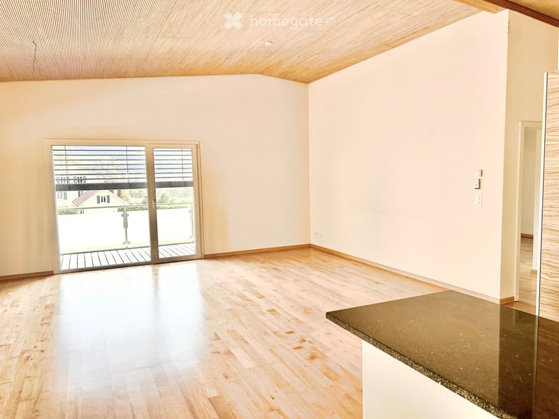Empty room with light wooden flooring, white walls, and a large sliding glass door leading to a balcony.