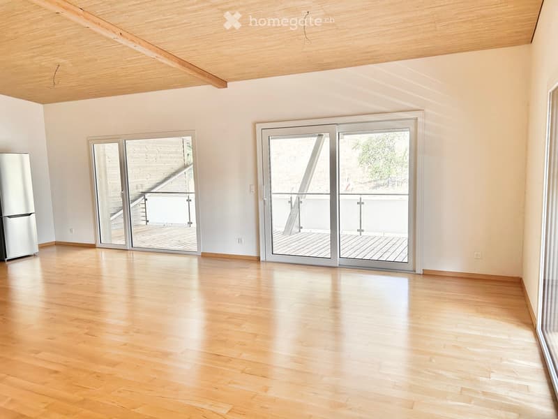 Empty room with light wooden flooring, white walls, and large sliding glass doors leading to a wooden deck area.
