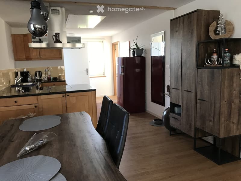 Open-plan kitchen and dining area with wooden cabinets, a central island, a dining table with chairs, and modern appliances.