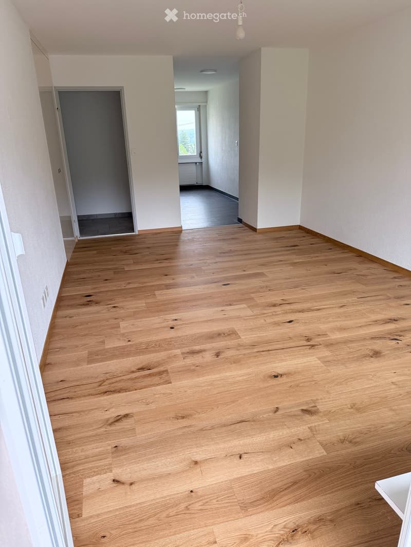 Empty hallway with light wooden flooring, white walls, and recessed lighting. Doors lead to adjacent rooms.