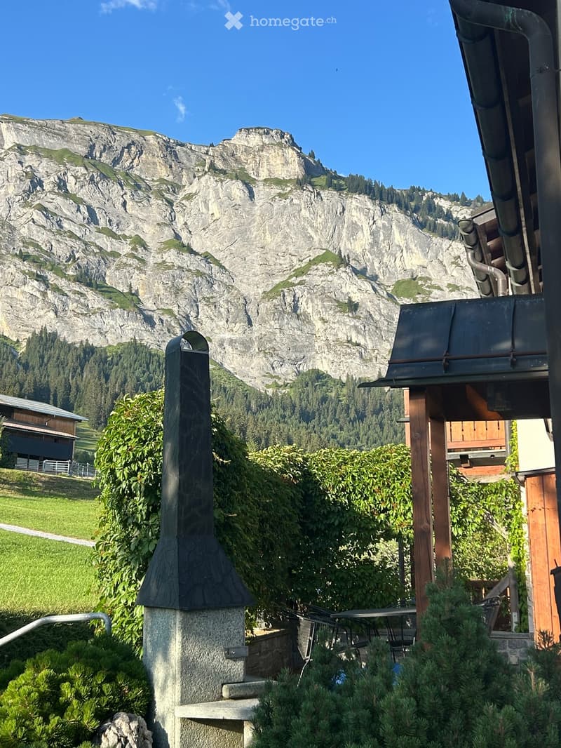 Outdoor area with a stone chimney, patio furniture, and a scenic mountain backdrop.