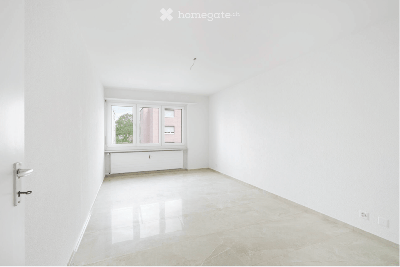 Empty room with white walls, tiled floor, and large window with multiple panes. No furniture or equipment present.