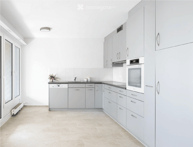 Modern kitchen with white cabinets, stainless steel appliances, and a tiled backsplash.