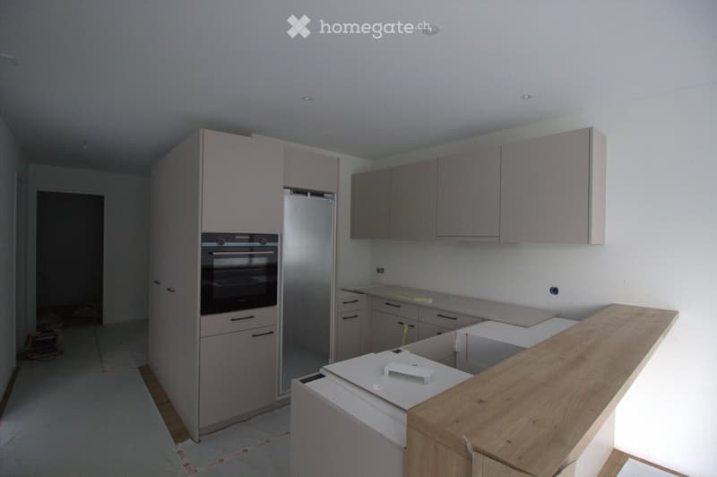 Modern kitchen with light grey cabinets, stainless steel appliances, and a wooden countertop.
