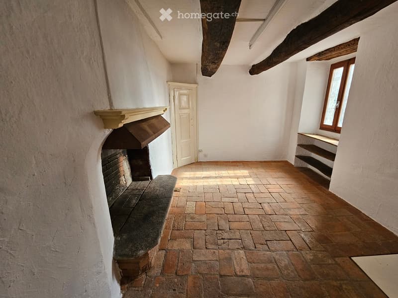 white walls, brick fireplace, wooden beams, wooden floor, window, door