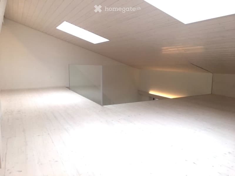 Completely empty room with white walls, wooden floor, and a glass partition. No furniture or equipment.