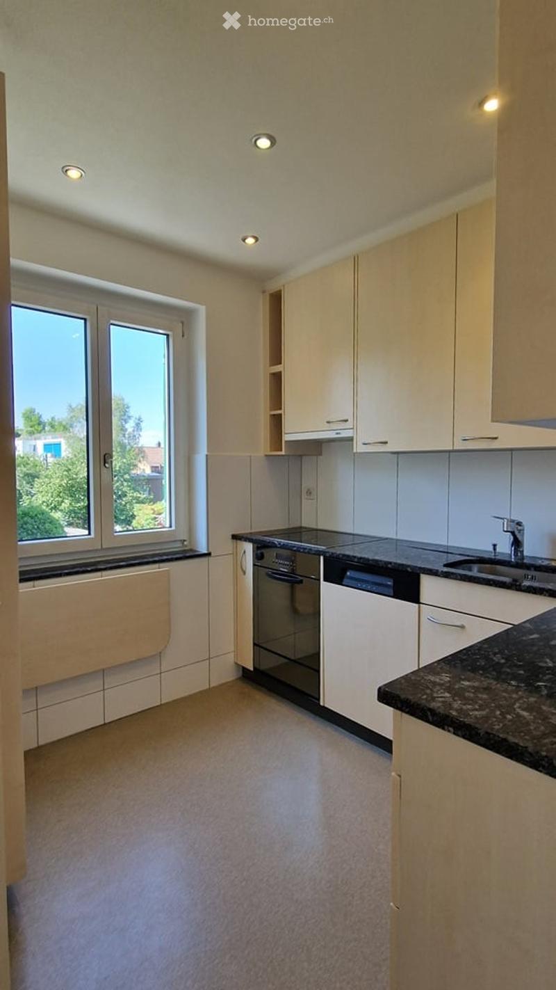 Modern kitchen with white cabinets, granite countertops, and built-in appliances including a dishwasher and sink.