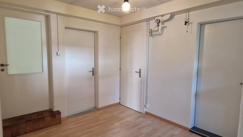 Empty room with wooden flooring, white walls, and multiple doors including a frosted glass door. No furniture or equipment present.
