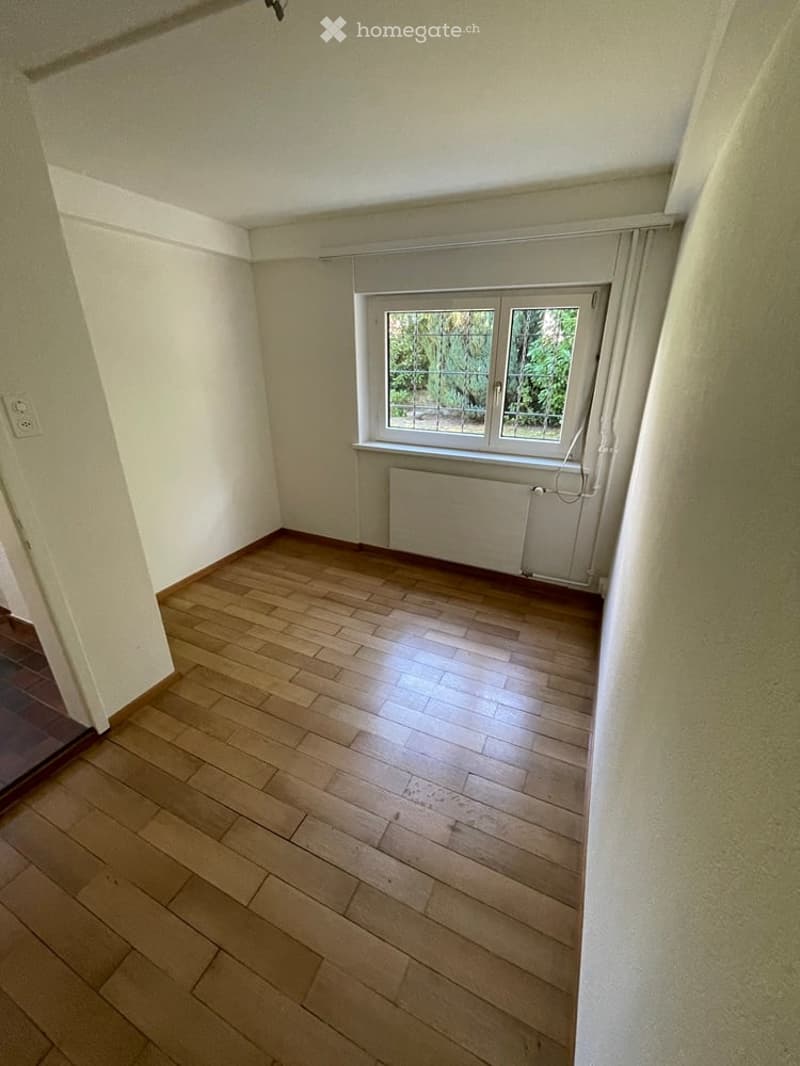 Empty room with wooden flooring, white walls, and a window with a radiator below it. No furniture or equipment is present.