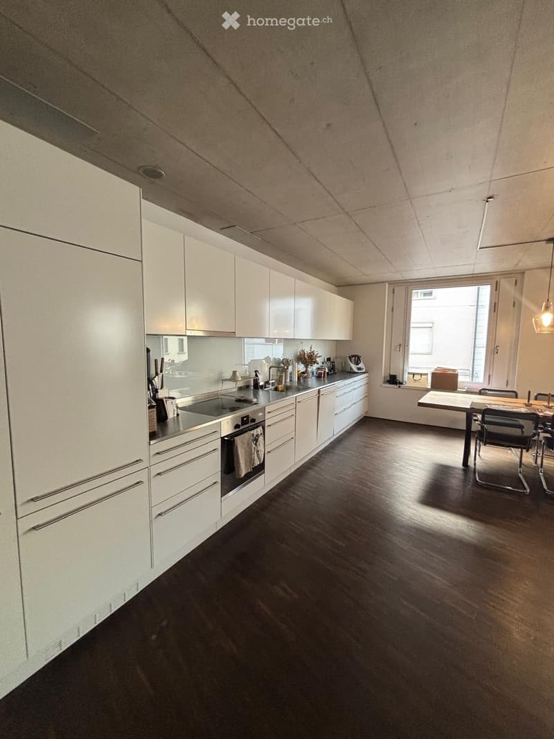 Modern kitchen with white cabinets, stainless steel appliances, and a dining area with a table and chairs.