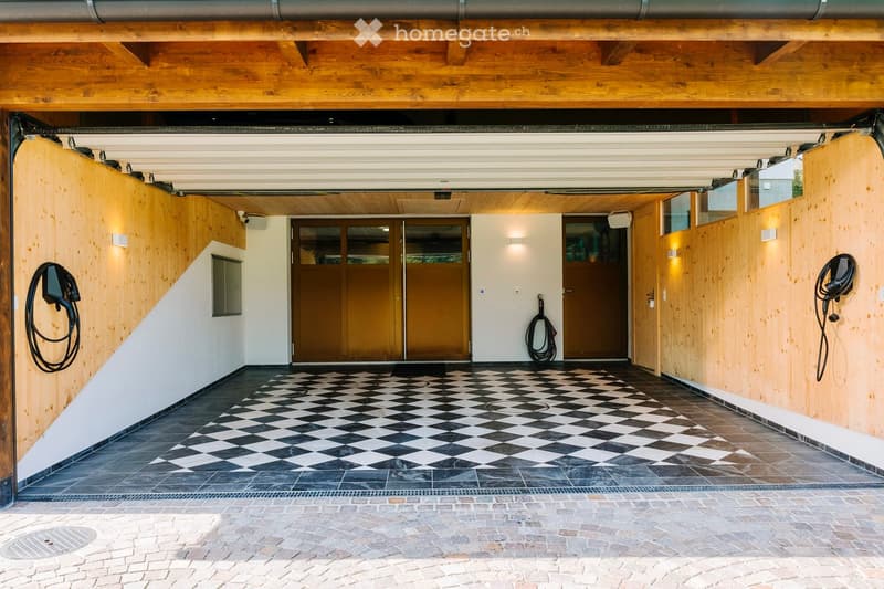 spacious carport with check-patterned flooring, wooden wall and ceiling, two car doors, charging stations