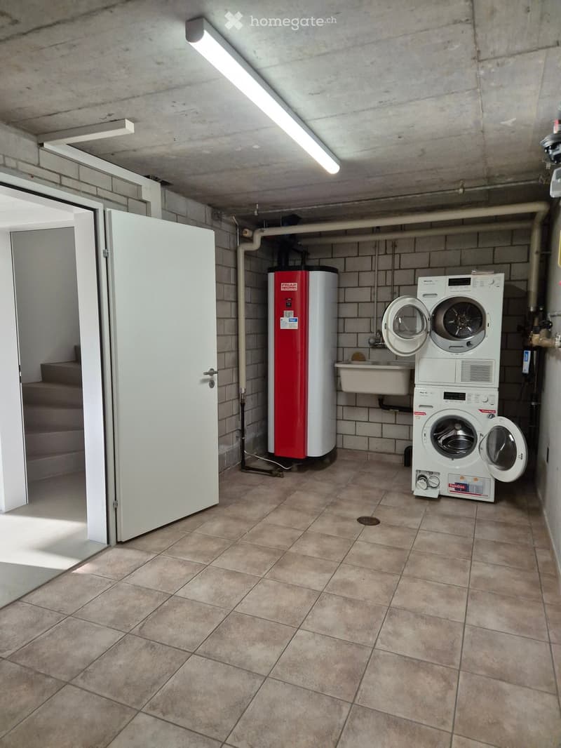 Utility room with tiled floor, white washing machine, water heater, and sink.