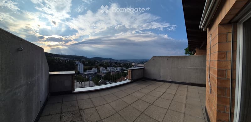 Balcony with tiled floor, metal railing, and a view of the cityscape and surrounding hills.