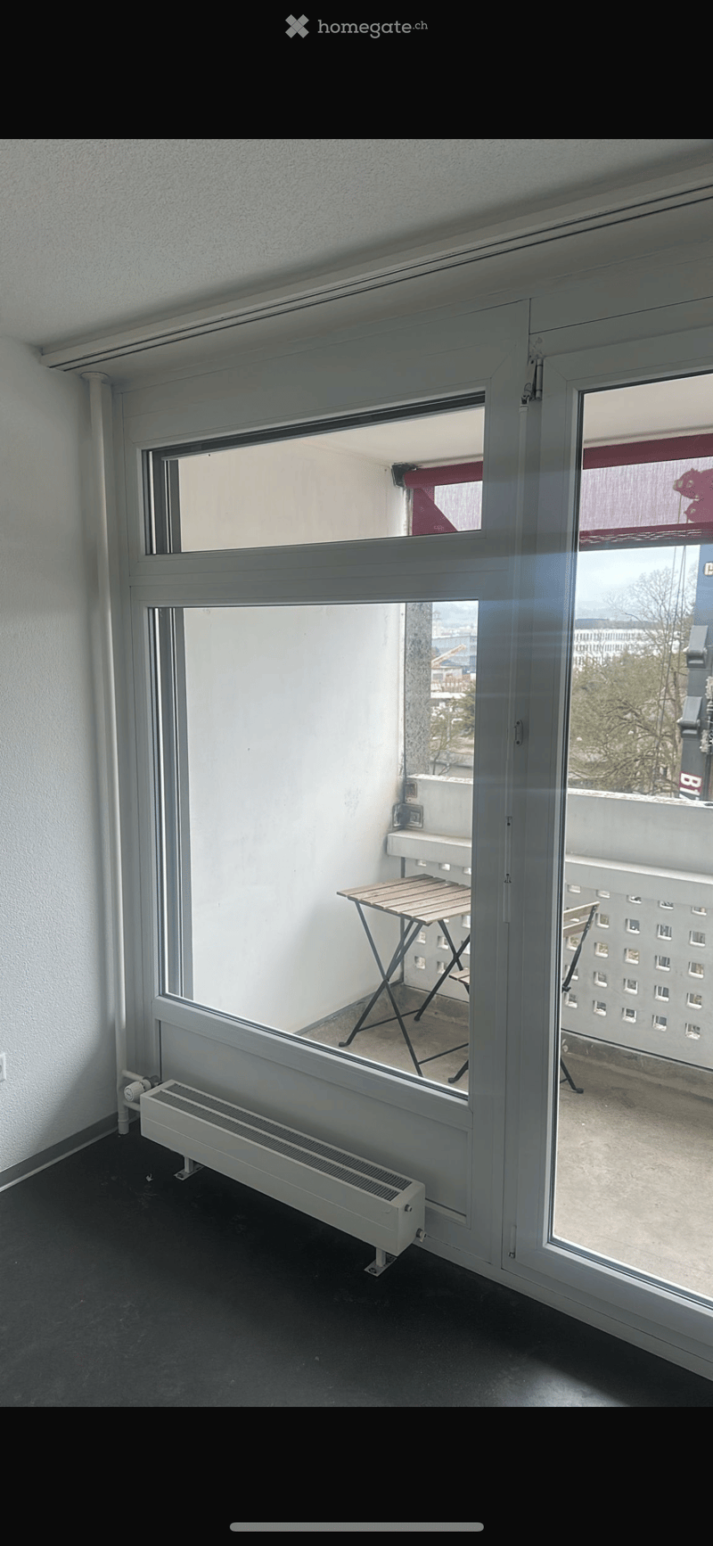Balcony with a small wooden table and a radiator visible in the adjacent room.
