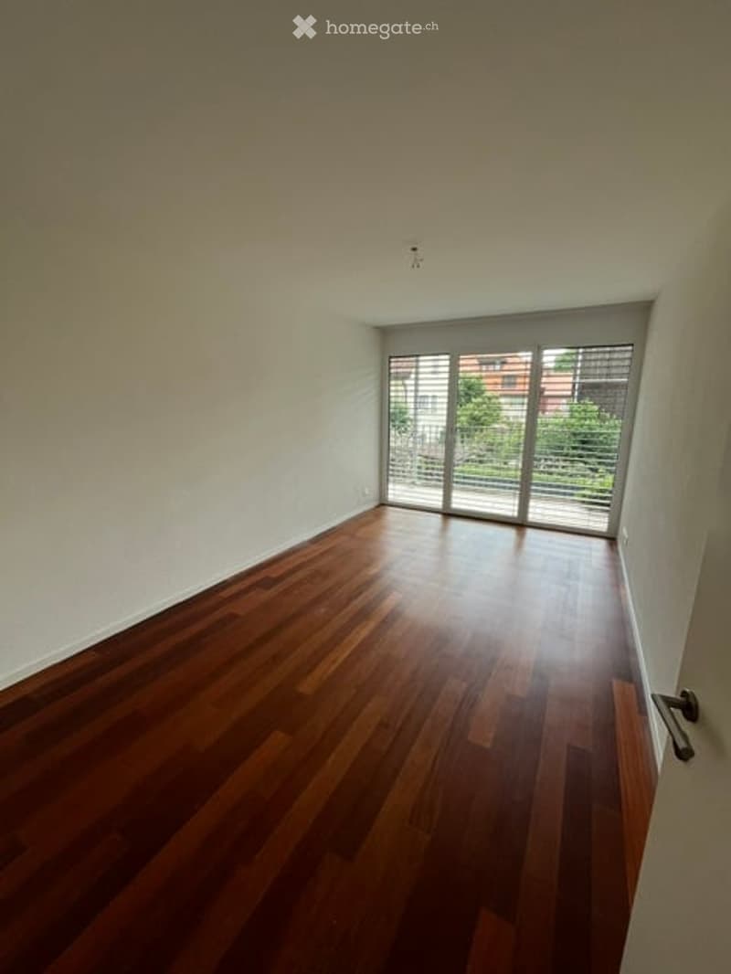 Empty room with wooden flooring and large sliding glass doors leading to an outdoor area.