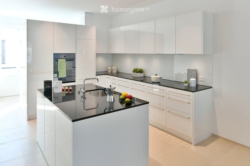 Modern kitchen with white cabinets, black countertops, stainless steel sink, and various appliances and decorative items.