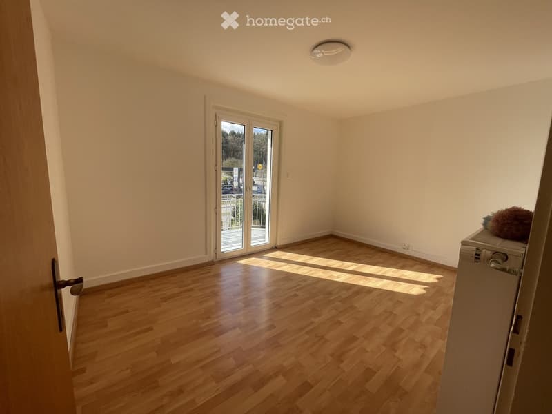 Empty room with wooden flooring, white walls, and a large sliding glass door leading to an outdoor area.