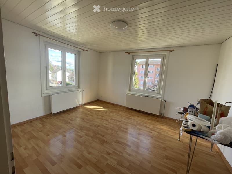 Empty room with wooden flooring, white walls, large windows, and radiators. No furniture or equipment present.