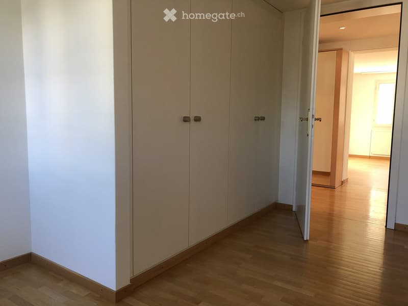 empty room with wooden floor, white walls, three built-in wardrobes, open door